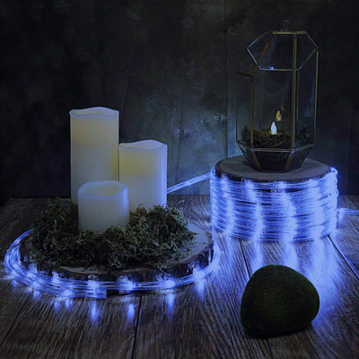 Decorative LED candle display with greenery and geometric lantern on a rustic table.