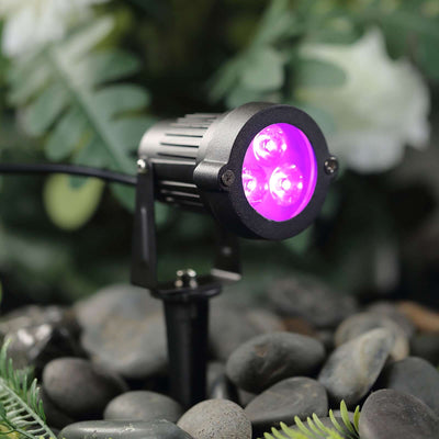Outdoor LED spotlight with purple light, ideal for garden or landscape illumination.