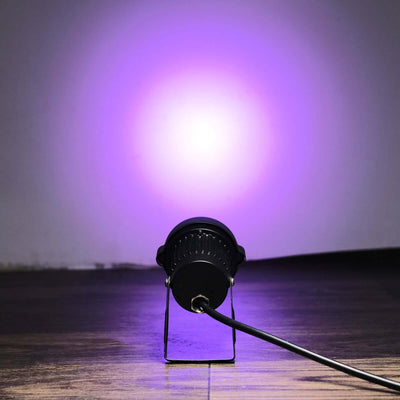 Purple LED spotlight on a stand illuminating a wall.