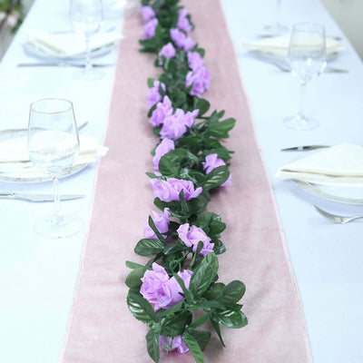 Floral table runner with purple flowers and greenery on a dining table.