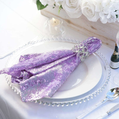 Purple sequined napkin elegantly arranged on a white plate at a dining table.