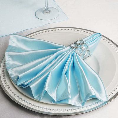 Elegant blue satin napkin elegantly draped on a plate with a decorative napkin ring.