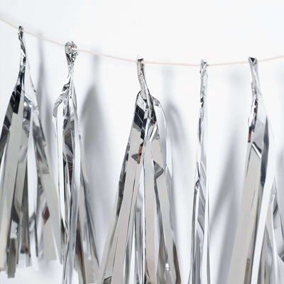 Silver foil garland decoration hanging on a string against a white background.