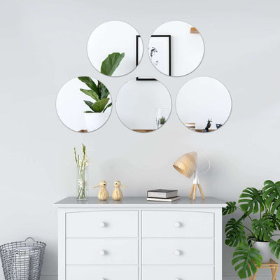 Decorative round mirrors arranged on a wall above a stylish dresser with decor.