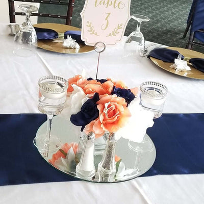 Elegant floral centerpiece with candles on a mirrored tray for table decoration.