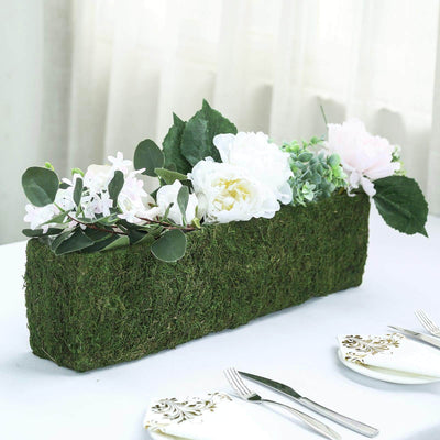 Decorative floral centerpiece in a moss-covered planter