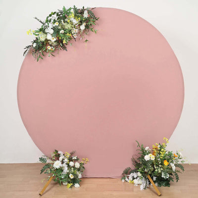 Round pink backdrop with floral arrangements at the base.