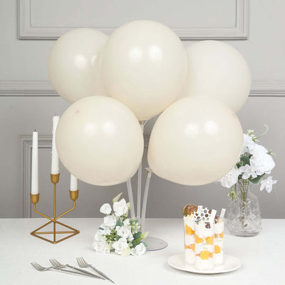 White balloons arranged with a dessert and floral decor on a table.