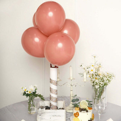 Pink balloons tied with a decorative ribbon at a table setting with flowers and candles.