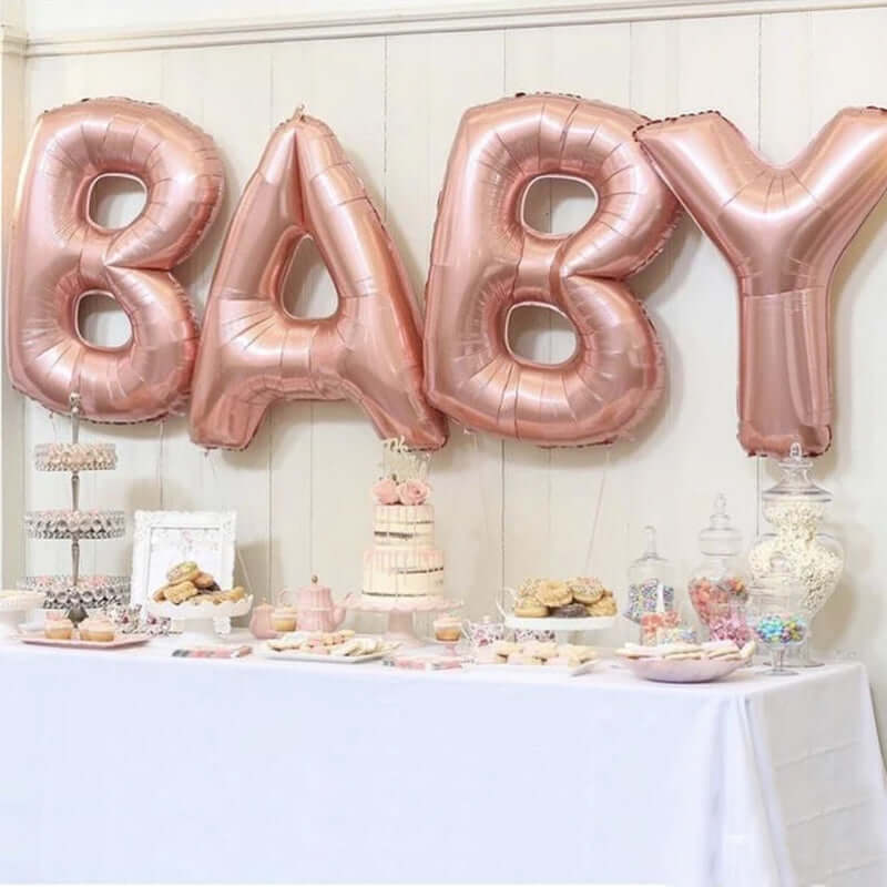 Rose gold "BABY" balloons at a festive dessert table for a baby shower.