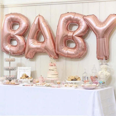 Rose gold "BABY" balloons at a festive dessert table for a baby shower.