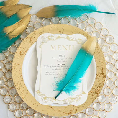 Elegant wedding menu with teal feather accent on decorative plate.