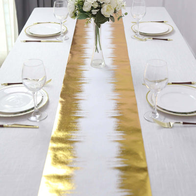 Gold and white table runner on a dining table with plates and glasses.