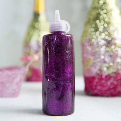 Purple glitter glue bottle on a plain background.