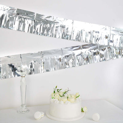 Elegant white cake adorned with flowers, set against a modern silver backdrop.