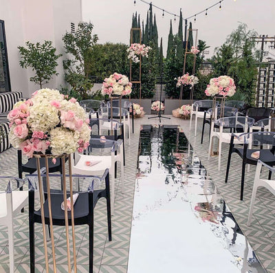 Wedding ceremony setup with floral arrangements and mirrored aisle.