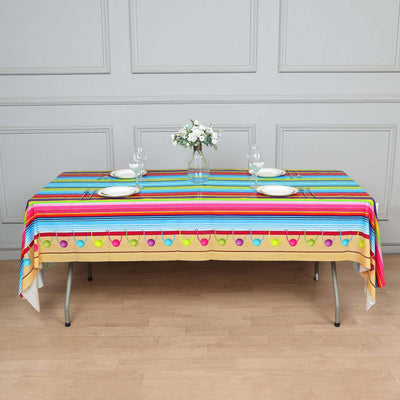 Colorful striped tablecloth with decorative trim on a dining table.