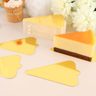 Golden cake slice decorations on a white surface.