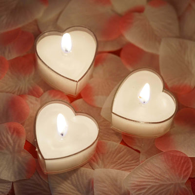 Heart-shaped candles on a bed of rose petals.