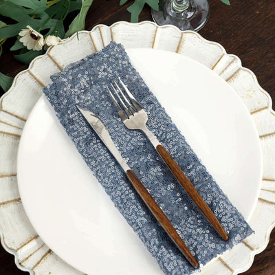 Elegant knife and fork on a blue sequined napkin atop a decorative plate.