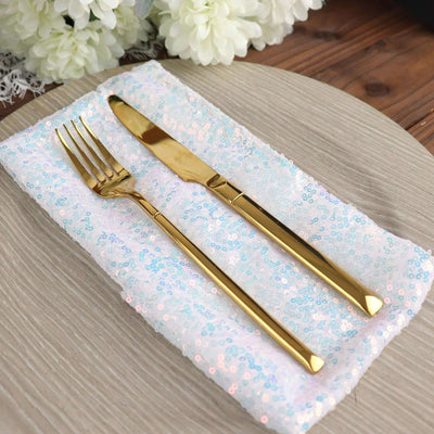 Gold fork and knife set on a sequin napkin with a wooden table backdrop.