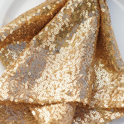 Gold sequin fabric draped elegantly on a white plate.