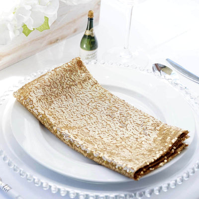 Gold sequin table napkin on a white plate, elegantly styled for dining.