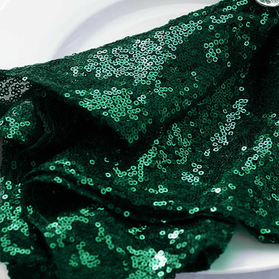 Green sequin fabric draped elegantly on a white surface.