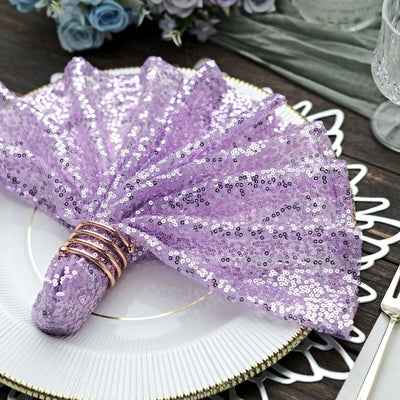 Purple sequin napkin fan with gold napkin rings on a decorative plate.