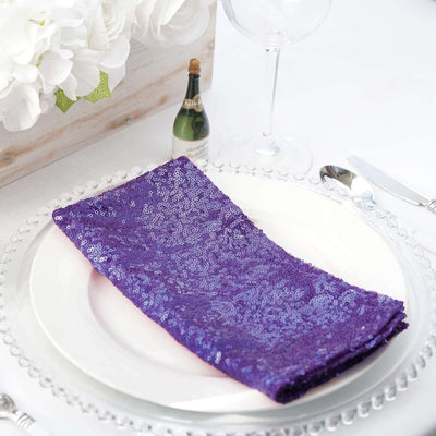 Purple sequin table napkin on a white plate with elegant table setting.