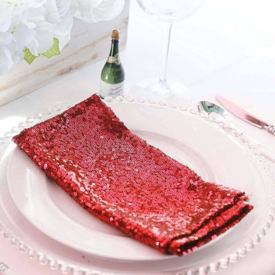 Red sequin table napkin elegantly displayed on a plate with decorative elements.
