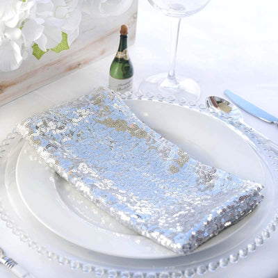Silver sequin napkin elegantly placed on a dinner plate with glassware and decor.