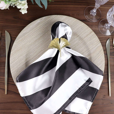 Elegant black and white striped napkin styled on a round wooden plate.