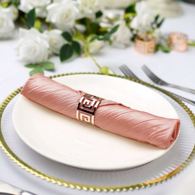 Elegant pink silk napkin wrapped with a decorative ring on a white plate.