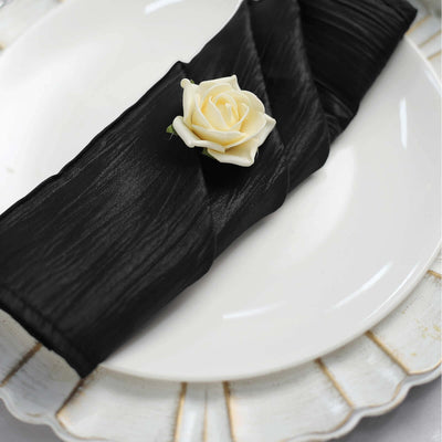 Black napkin with a white rose on a plate setting.