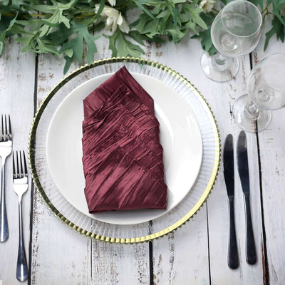 Elegant burgundy napkin on a white plate with decorative charger and cutlery.