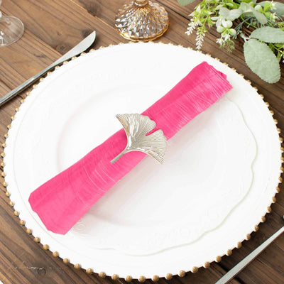 Pink napkin with silver napkin ring on a decorative plate.