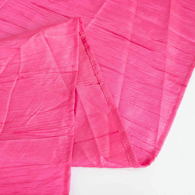 Pink crinkled fabric draped elegantly on a white background.