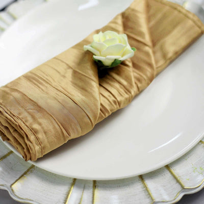Gold satin napkin elegantly folded on a white plate with a decorative flower.
