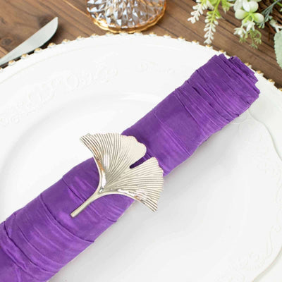 Purple napkin with silver ginkgo leaf napkin ring on an elegant plate.