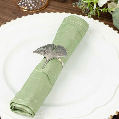 Silver ginkgo leaf napkin holder on a green napkin atop an elegant white plate.