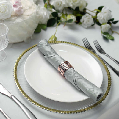 Elegant table setting with a silver napkin and decorative ring on a white plate.