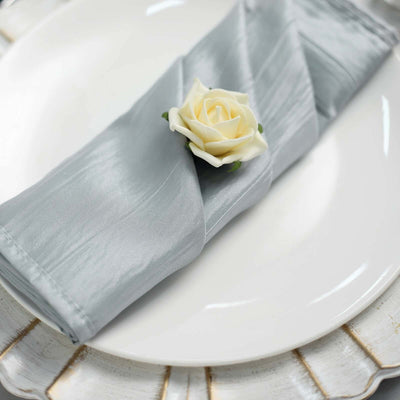 Silver satin napkin elegantly folded with a white rose on a decorative plate.