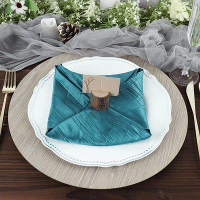 Teal satin napkin elegantly folded on a white plate with a natural wood holder.