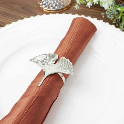 Ginkgo leaf napkin holder on a brown napkin at a dining table.