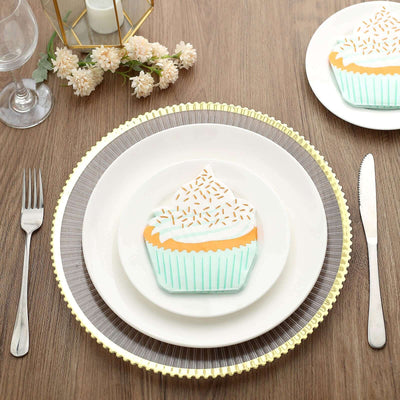 Cupcake-shaped plate on a dining table with cutlery and floral decor.