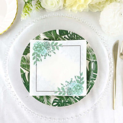 Decorative plate with tropical leaves and floral napkin on a table setting.