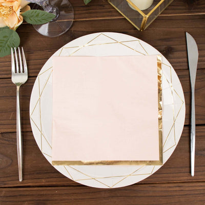 Elegant pink napkin on a decorative plate with silver cutlery on a wooden table.