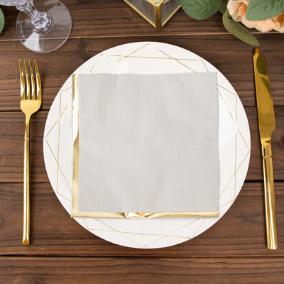 Elegant gold-accented dinner plate with folded napkin on a rustic wooden table.