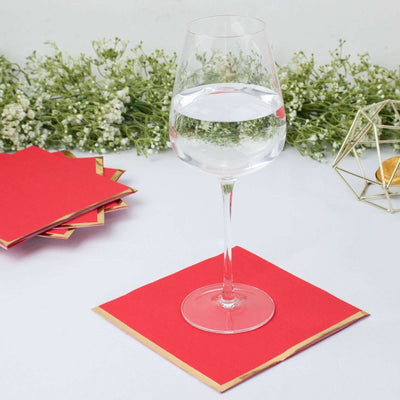 Elegant glass of water on a red and gold coaster with greenery backdrop.